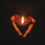 Person mit haenden auf der brust in stiller selbstreflexion bei warmem licht