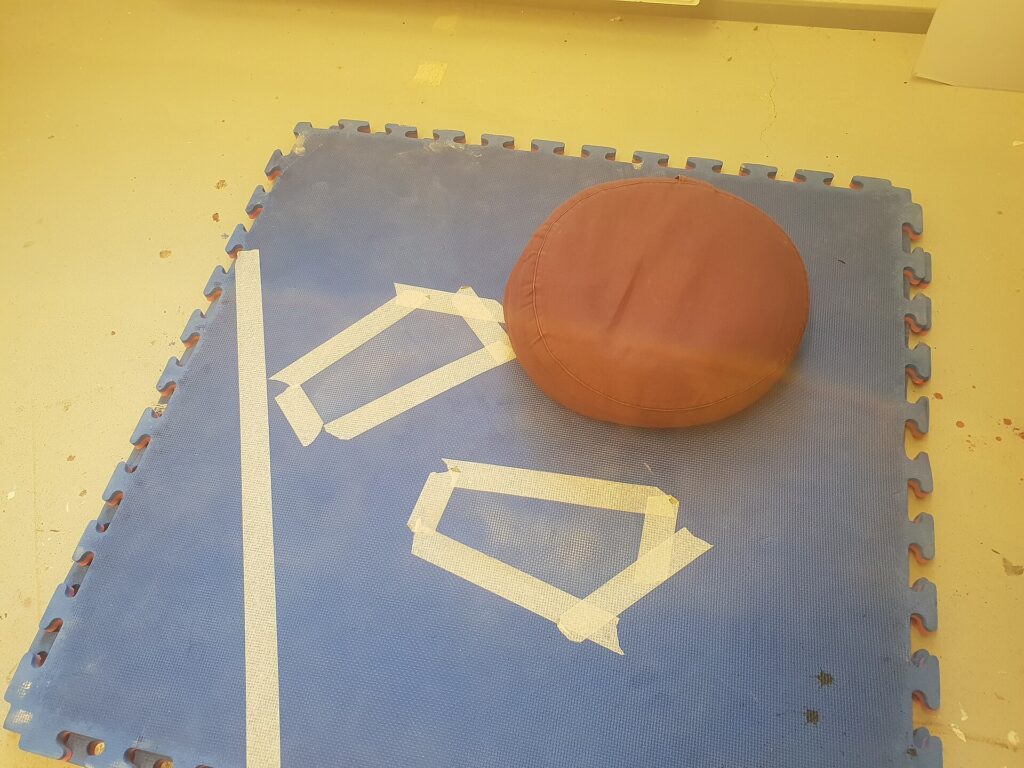 Rundes Sitzkissen steht auf einem Teppich in einem schlichten Raum mit Tageslicht