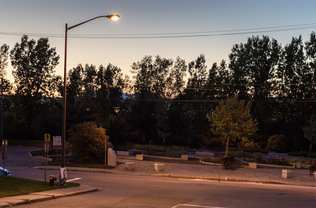 Eine leuchtende Stra&szlig;enlaterne &uuml;ber einem leeren Gehweg in der fr&uuml;hen D&auml;mmerung