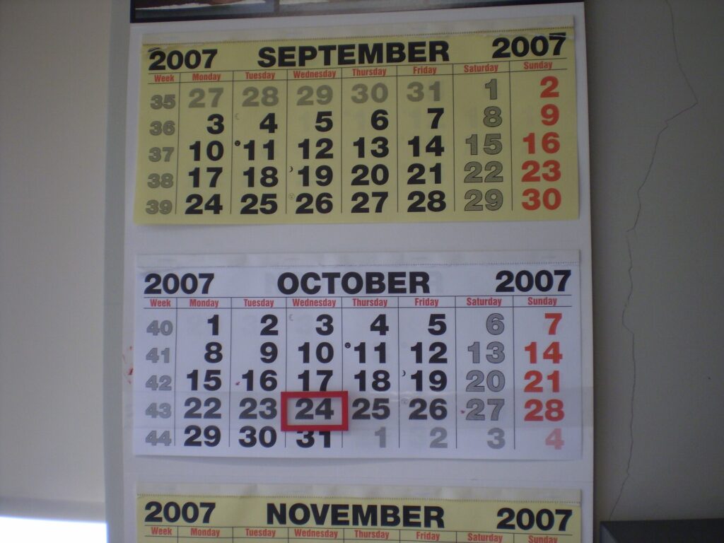 Aufgeschlagener Wandkalender mit handschriftlichen Eintr&auml;gen an einer hellen Wand