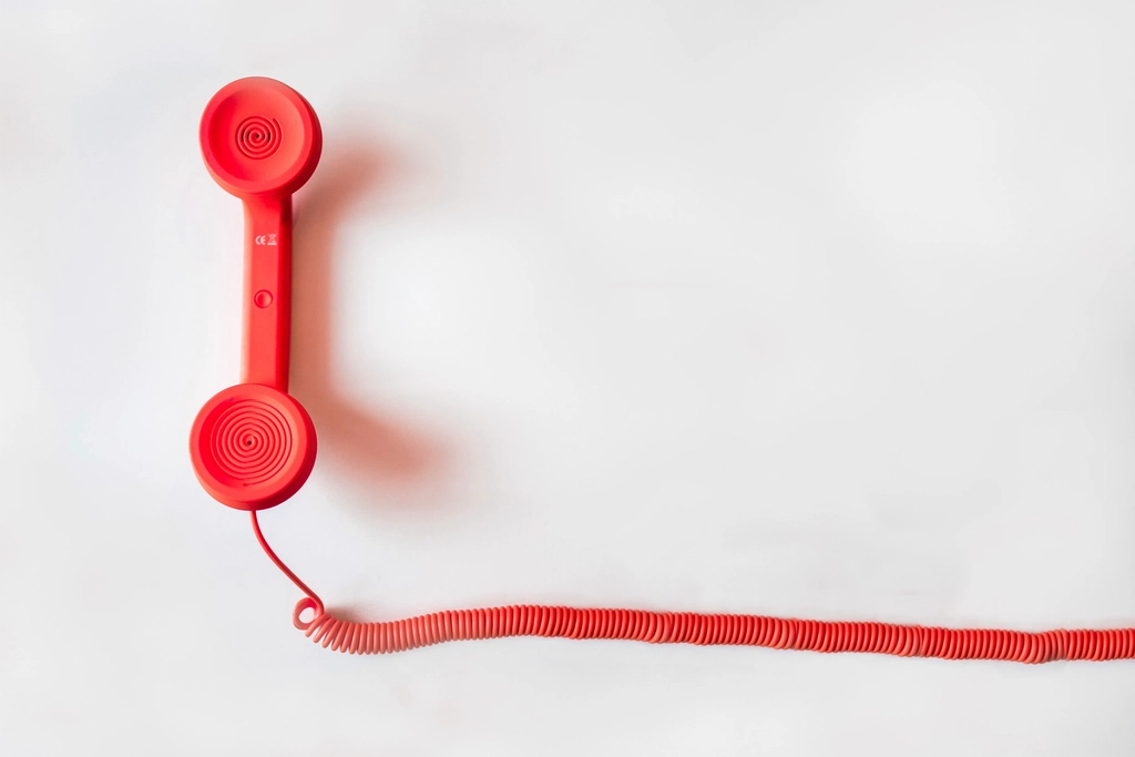Telefon mit aufgelegtem H&ouml;rer steht auf einem Tisch neben einem beschriebenen Block