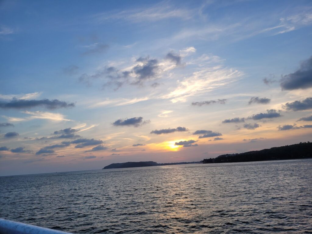 Die Sonne geht über einem ruhigen Meer unter und taucht den Himmel in warmes Licht