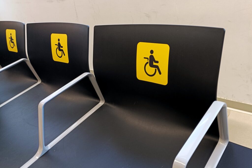 Leere Stuhlreihe in einem hellen Wartezimmer mit einem kleinen Tisch daneben