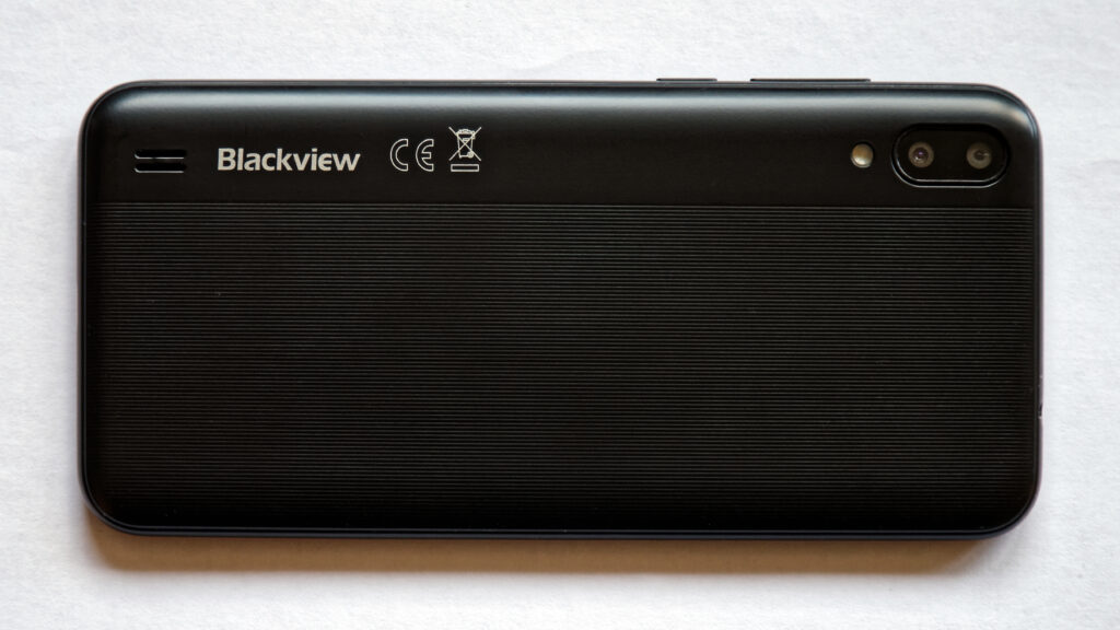 Ein Smartphone liegt mit dem Display nach unten auf einem schlichten Holztisch