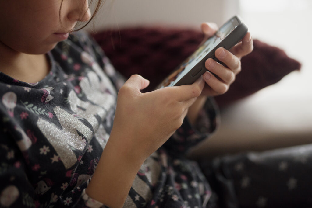 Ein Smartphone-Bildschirm mit App-Symbolen liegt auf einem Holztisch neben einer Tasse