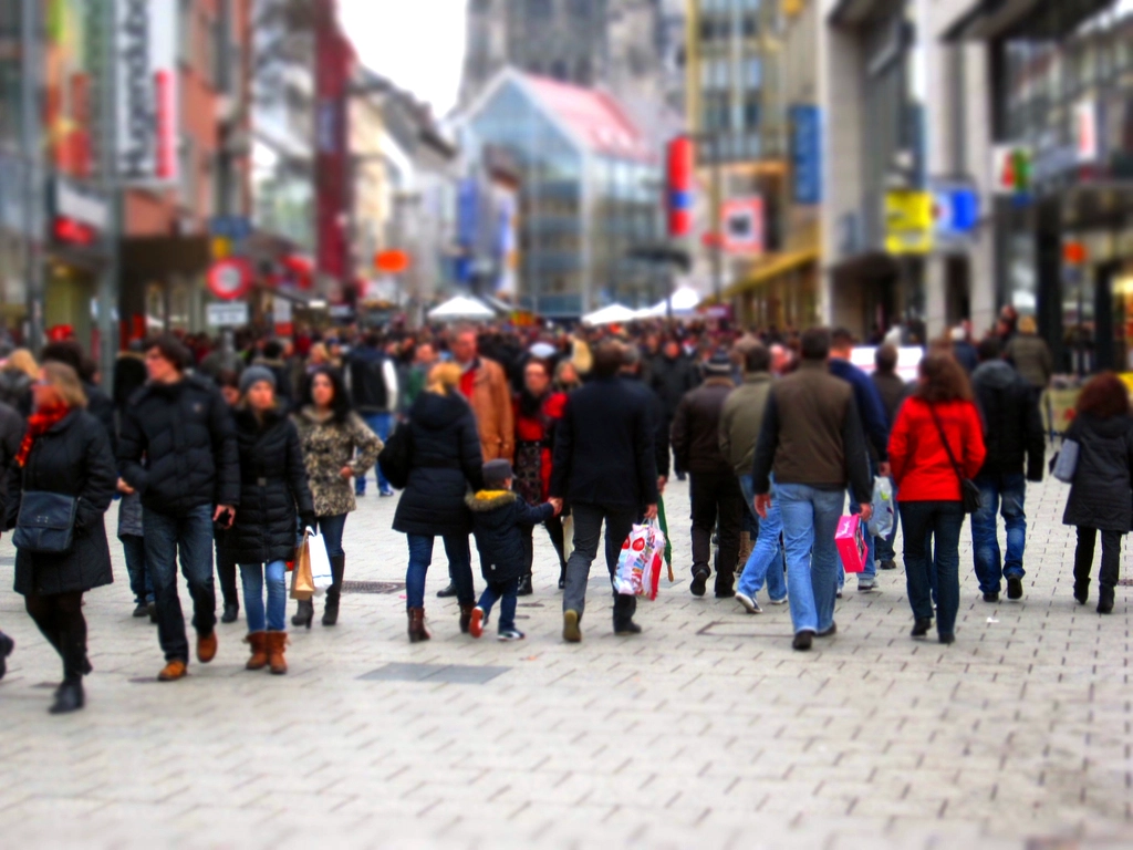 Viele Menschen gehen dicht nebeneinander über eine belebte Straße in der Stadt
